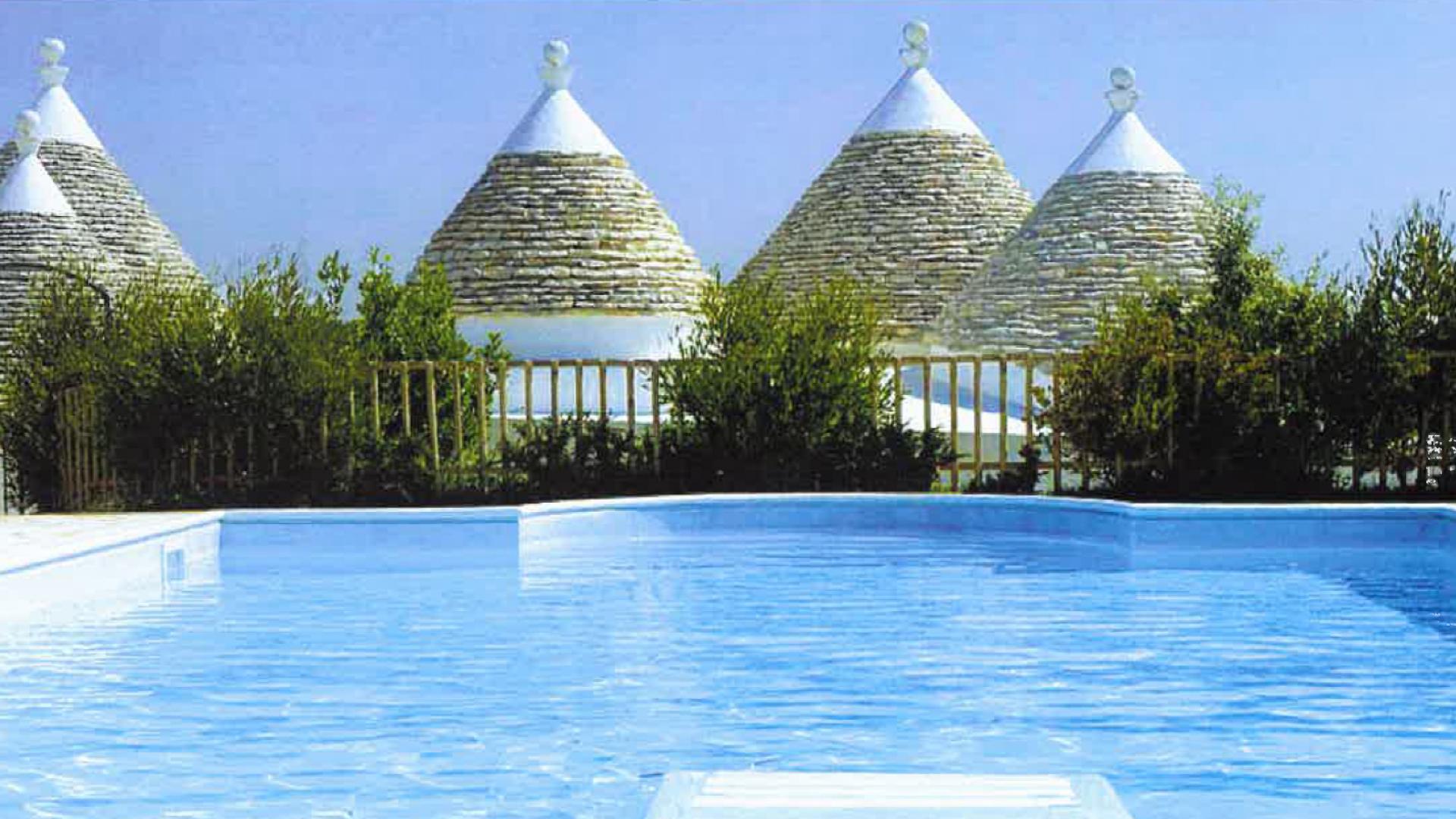 Piscina di fronte ai trulli, tipiche costruzioni con tetto conico in pietra.