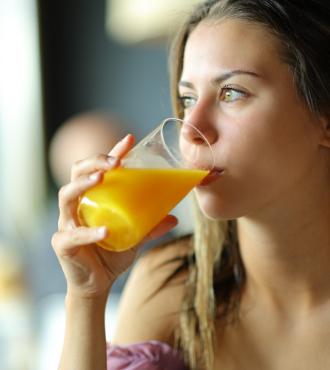 Ragazza che beve succo d'arancia, sguardo pensieroso, atmosfera rilassata.