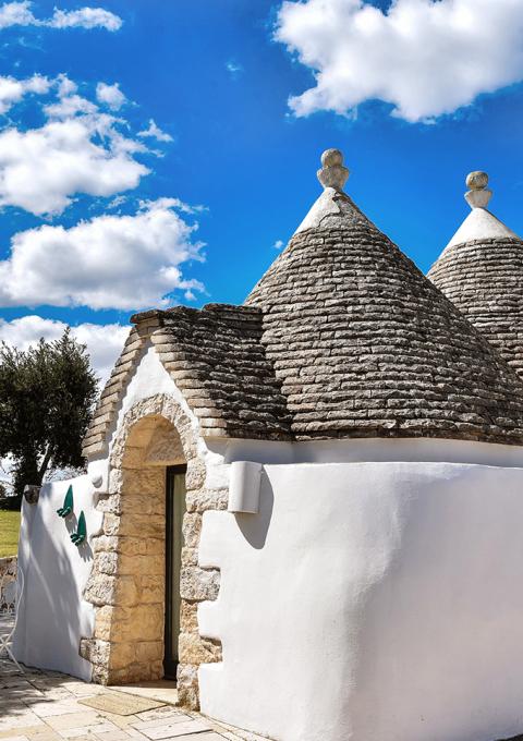 Trulli pugliesi incantati sotto cielo azzurro, un'oasi di pace e bellezza.
