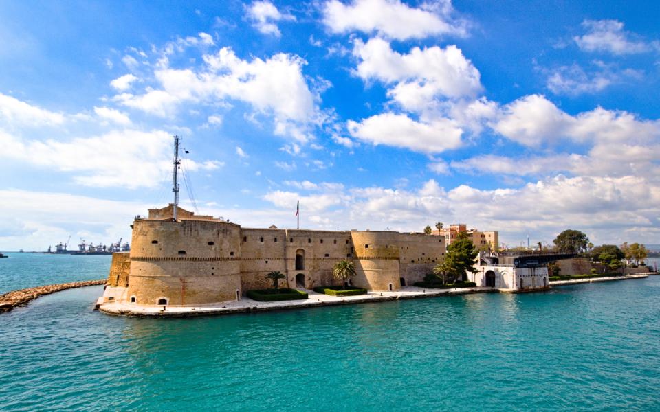 Castello Aragonese di Taranto, fortezza storica circondata dal mare e cielo azzurro.